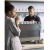 This image is a front-side view of the Rancilio Specialty RS1 espresso machine showcase picture with barista and customer with drink.
